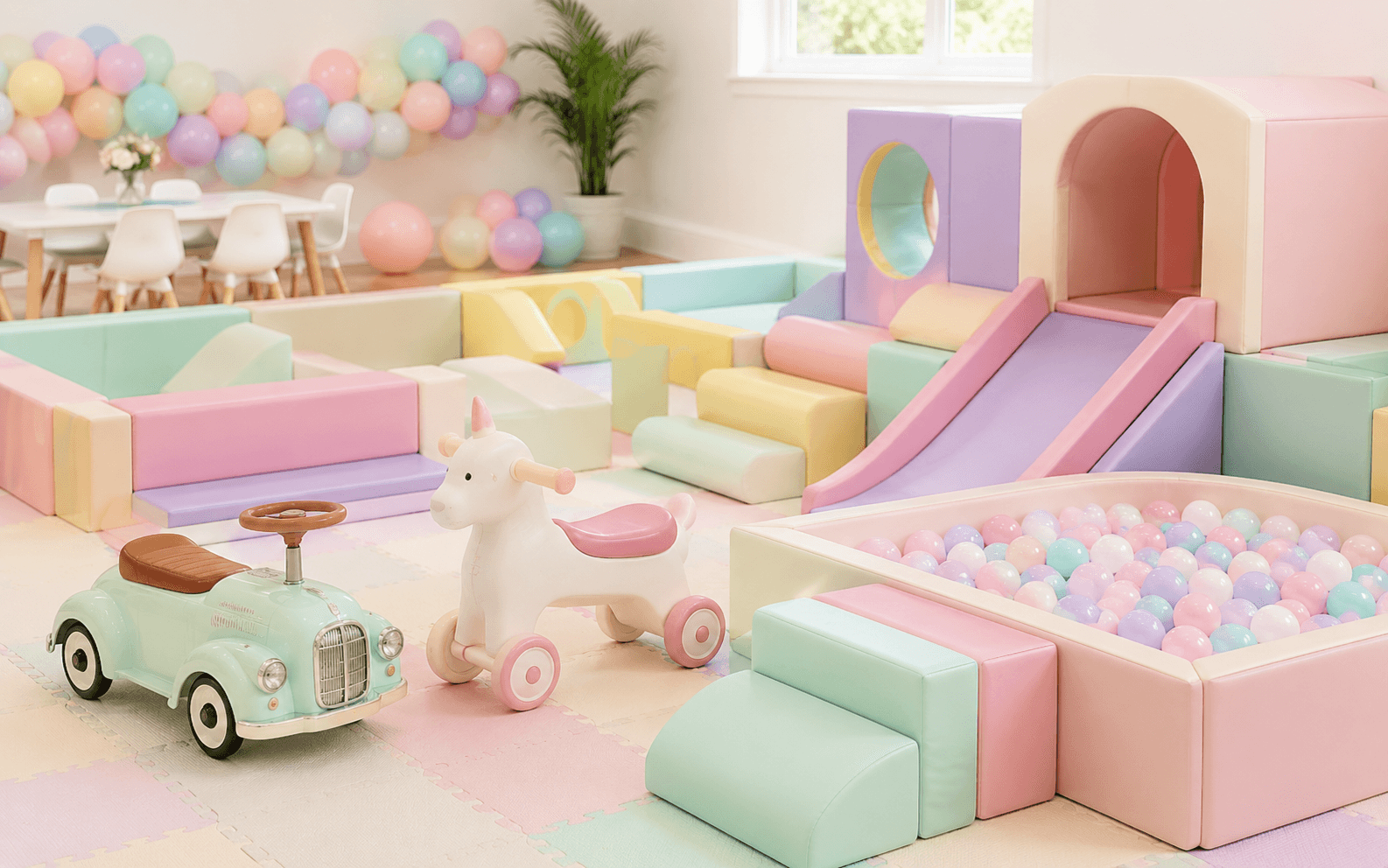 Pastel soft play, ball pit and ride-on equipment for a children's party